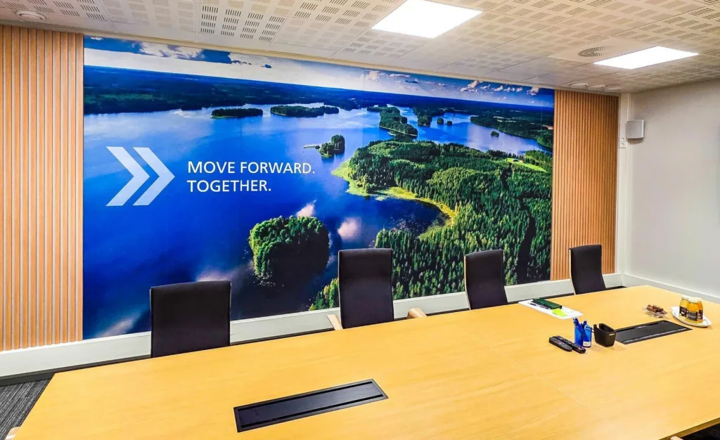 Suurkuvatulostettu seinägrafiikka neuvotteluhuoneessa, maisemakuva ja teksti "Move Forward Together"